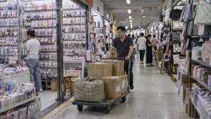 a worker moving cartons through an aisle in a Yiwu-style wholesale market.